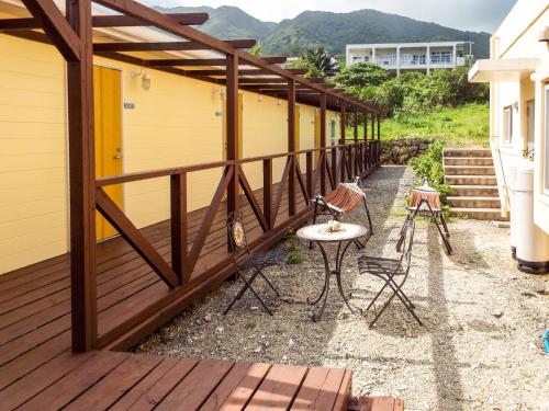 a wooden deck with a table and chairs on it at AsobiBASE Yamabare-House in Ishigaki Island