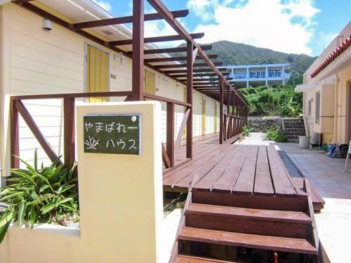 a wooden walkway with a sign on the side of a building at AsobiBASE Yamabare-House in Ishigaki Island