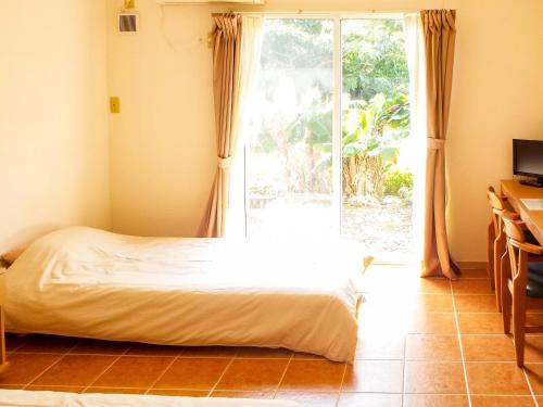 ein Schlafzimmer mit einem Bett und einem großen Fenster in der Unterkunft AsobiBASE Yamabare-House in Ishigaki-jima