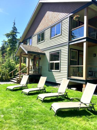 a group of lounge chairs in the grass in front of a house at Cobble Wood and Bird Sanctuary Guest Houses in Tofino