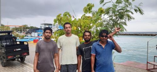 a group of men standing next to the water at Liberty Guesthouse Maldives in Mahibadhoo