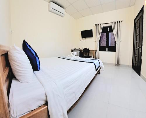 1 dormitorio con 1 cama y TV en Blue Beach Homestay, en Hoi An