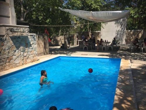 una niñita en una piscina con una pelota en Hospedaje Papagrande, en Homún