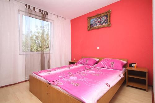 Schlafzimmer mit einem Bett mit rosa Bettwäsche und einem Fenster in der Unterkunft Apartments with a parking space Stari Grad, Hvar - 8752 in Stari Grad