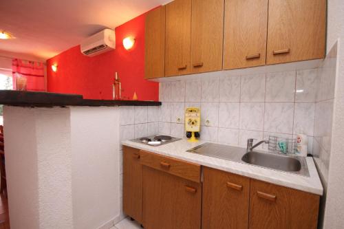eine kleine Küche mit einem Waschbecken und einer roten Wand in der Unterkunft Apartments with a parking space Stari Grad, Hvar - 8752 in Stari Grad