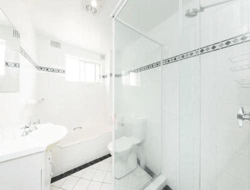 a white bathroom with a sink and a shower at At the Beach, Debra Court Unit 5 in Forster