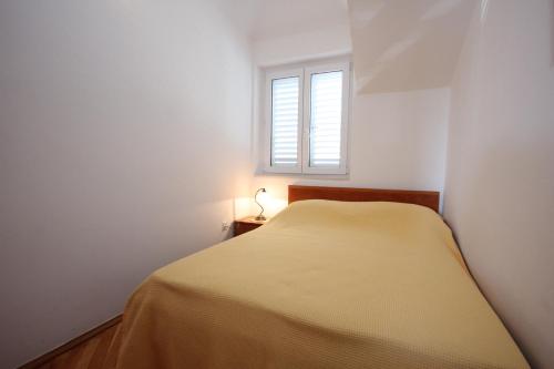 a small bedroom with a bed and a window at Apartments with a parking space Cavtat, Dubrovnik - 9032 in Cavtat
