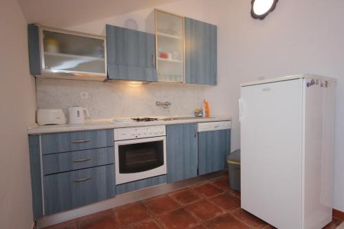 a kitchen with blue cabinets and a white refrigerator at Apartments with a parking space Cavtat, Dubrovnik - 9032 in Cavtat