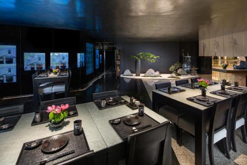 a dining room with black tables and chairs with flowers at The Garden Hotel Guangzhou - Discover 26 cultural treasures with hotel Golden Tour Guide in Guangzhou