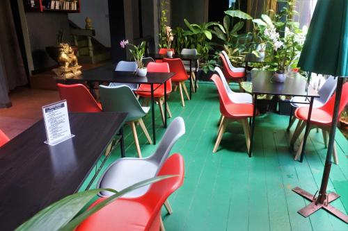 um restaurante com cadeiras vermelhas, mesas e plantas em Hi Karon Beach em Praia de Karon