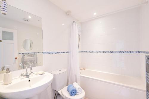 a white bathroom with a sink and a tub and a toilet at Meledor in Marazion