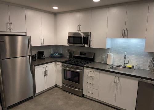 una cocina con armarios blancos y electrodomésticos de acero inoxidable en DTLA home away en Los Ángeles