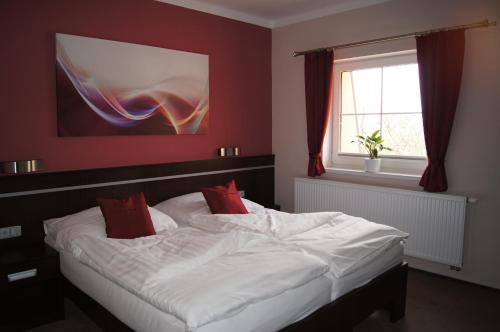 a bedroom with a bed with white sheets and red pillows at Penzion Na Netřebě in Pardubice