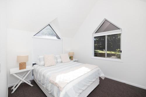 um quarto branco com uma cama e uma janela em Fairway Views em Mollymook