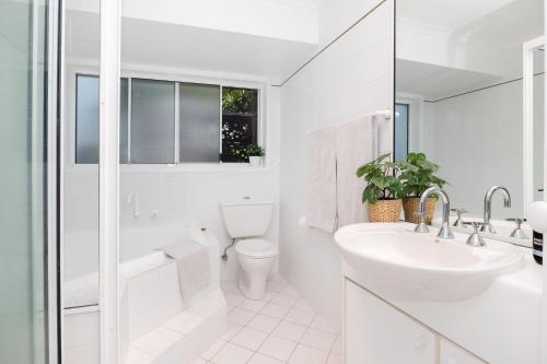 uma casa de banho branca com um lavatório e um WC em Fairway Views em Mollymook