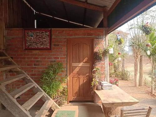 un edificio de ladrillo con una puerta de madera y un banco en Battambang Eco Stay, en Phumĭ Ândong Pring