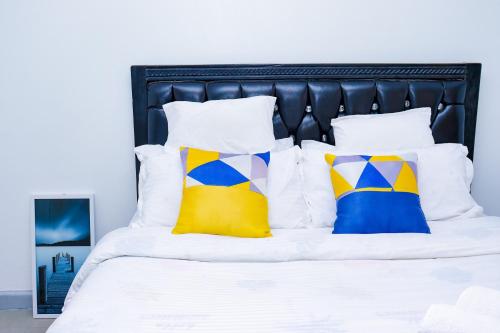 a white bed with colorful pillows on it at Homely Homes in Nairobi
