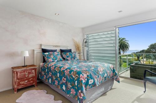 a bedroom with a bed and a large window at Pohutukawa Paradise - Ōhope Holiday Apartment in Ohope Beach
