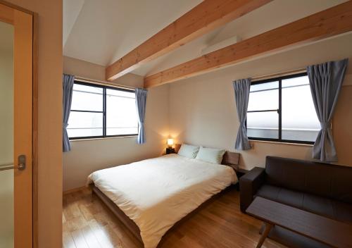 a bedroom with a bed and a couch and two windows at Guesthouse Soi in Kyoto
