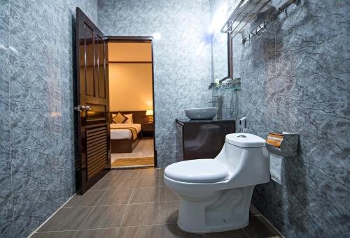 uma casa de banho com WC e um quarto com cama em Vang Vieng Freedom Star's Hotel em Vang Vieng