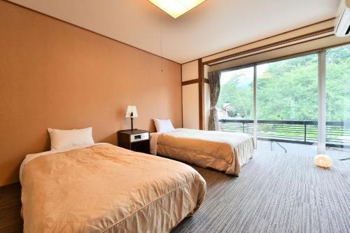 a bedroom with two beds and a large window at Arya Hotel Alpin Route / Vacation STAY 8236 in Omachi