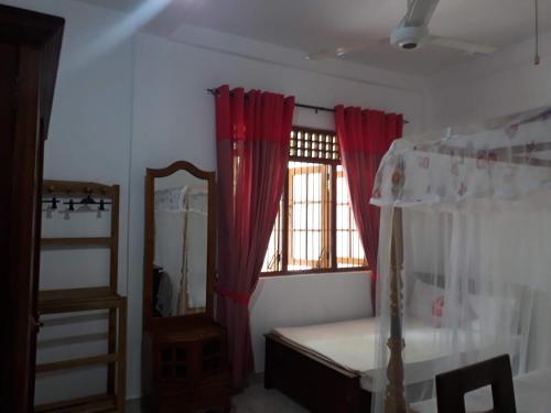 een slaapkamer met een bed en een raam met rode gordijnen bij Green Villa Home in Anuradhapura