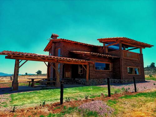 a wooden house with a picnic table in front of it at Cabaña lejos de la ciudad Maxi in Acaxochitlán