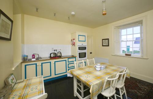 a kitchen with a table and a sink and a table and chairs at Loop Head Lightkeeper's House in Kilbaha