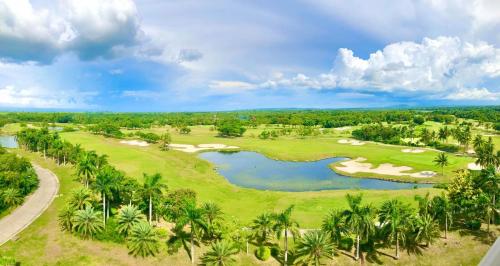 an overhead view of a golf course with a lake and palm trees at Queens Island Golf and Resort in Medellin