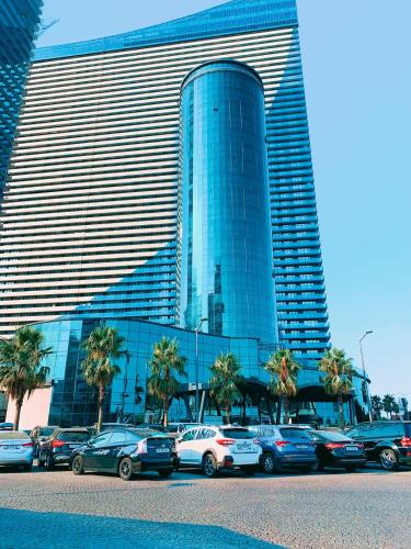 a parking lot with cars parked in front of a large building at King Sky Tower Hotel in Batumi