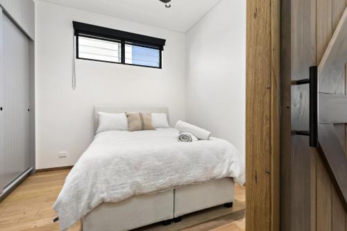 a bedroom with a bed with white sheets and a window at The Stables at the Hill in Newcastle