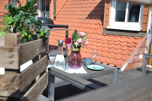 a table with a vase of flowers and wine glasses at Gemütliche Dachwohnung mit kleiner oder großer Dachterrasse nebeneinander in Wolmirstedt