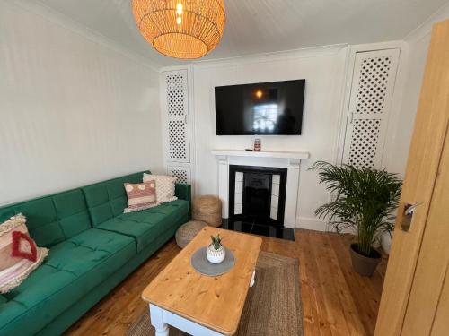 a living room with a green couch and a fireplace at Casa Cozy in Torquay