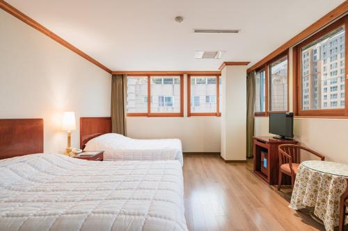 a hotel room with two beds and a television at Samhaein Hotel in Jeju