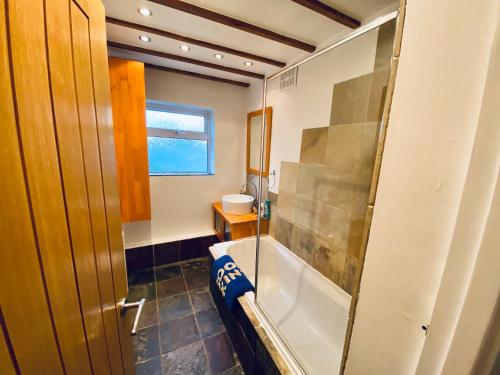 ein Badezimmer mit einer Badewanne und einem Waschbecken in der Unterkunft Cloud9SA at The Royston Byfleet in Byfleet
