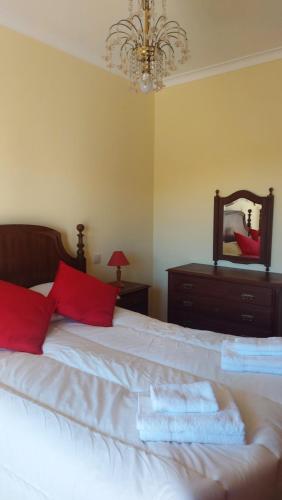 a bedroom with a bed with red pillows and a mirror at Vila Maria in Vila Praia de Âncora