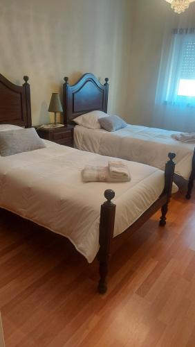 two beds in a room with wooden floors at Vila Maria in Vila Praia de Âncora