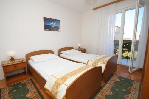 two beds in a room with a window at Apartments with a parking space Komiza, Vis - 8866 in Komiža
