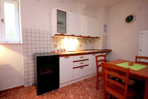 eine Küche mit weißen Schränken, einem Tisch und einem Herd in der Unterkunft Apartments by the sea Vis - 8932 in Vis