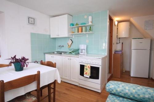 - une cuisine avec une table et une cuisinière blanche dans l'établissement Apartments and rooms by the sea Komiza, Vis - 8910, à Komiža