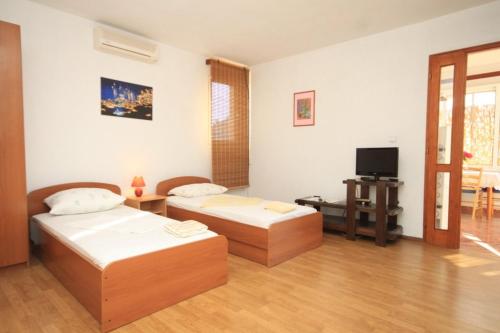 a hotel room with two beds and a television at Apartments with WiFi Komiza, Vis - 8911 in Komiža