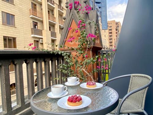 a table on a balcony with two cups and two desserts at Heart of Yerevan - City Center Luxury Apartments in Yerevan