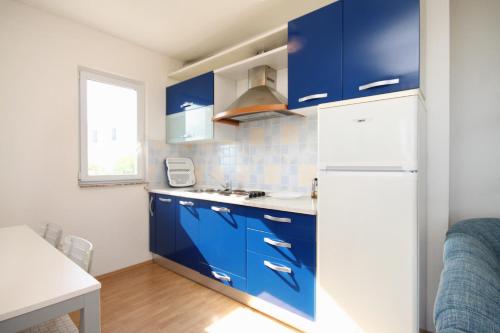 a kitchen with blue cabinets and a white refrigerator at Apartments with a parking space Brgujac, Vis - 8919 in Rukavac