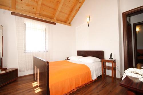 sypialnia z łóżkiem z pomarańczowym kocem w obiekcie Apartments with a parking space Podspilje, Vis - 8915 w mieście Vis