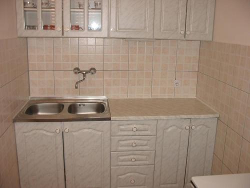a kitchen with a sink and white cabinets at Apartments by the sea Rogoznica - 9127 in Rogoznica