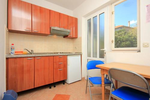 Apartments by the sea Brna, Korcula - 9139 في برنا: مطبخ بدولاب خشبي وطاولة وكراسي