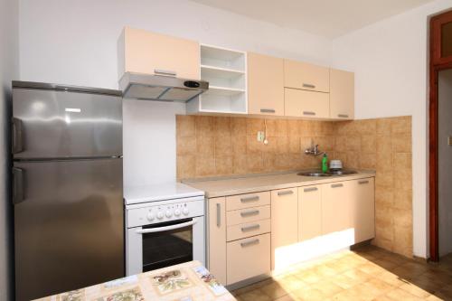 a kitchen with a stainless steel refrigerator and white cabinets at Apartments by the sea Cove Milna - Zastrazisce, Hvar - 8951 in Zastražišće