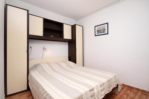 ein Schlafzimmer mit einem Bett und einer weißen Wand in der Unterkunft Apartments by the sea Cove Milna - Zastrazisce, Hvar - 8951 in Zastražišće
