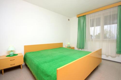 a bedroom with a green bed and a window at Apartments by the sea Prigradica, Korcula - 9141 in Blato