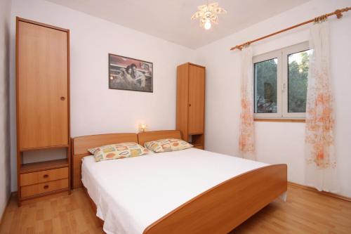 un dormitorio con una cama y una ventana en Apartments by the sea Brna, Korcula - 9159, en Smokvica